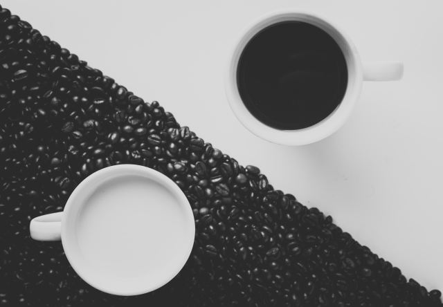 striking black and white image of coffee beans, coffee in a cup and milk in a cup...a bit like a yin yang symbol but triangles with the inset contrasting circles of colour