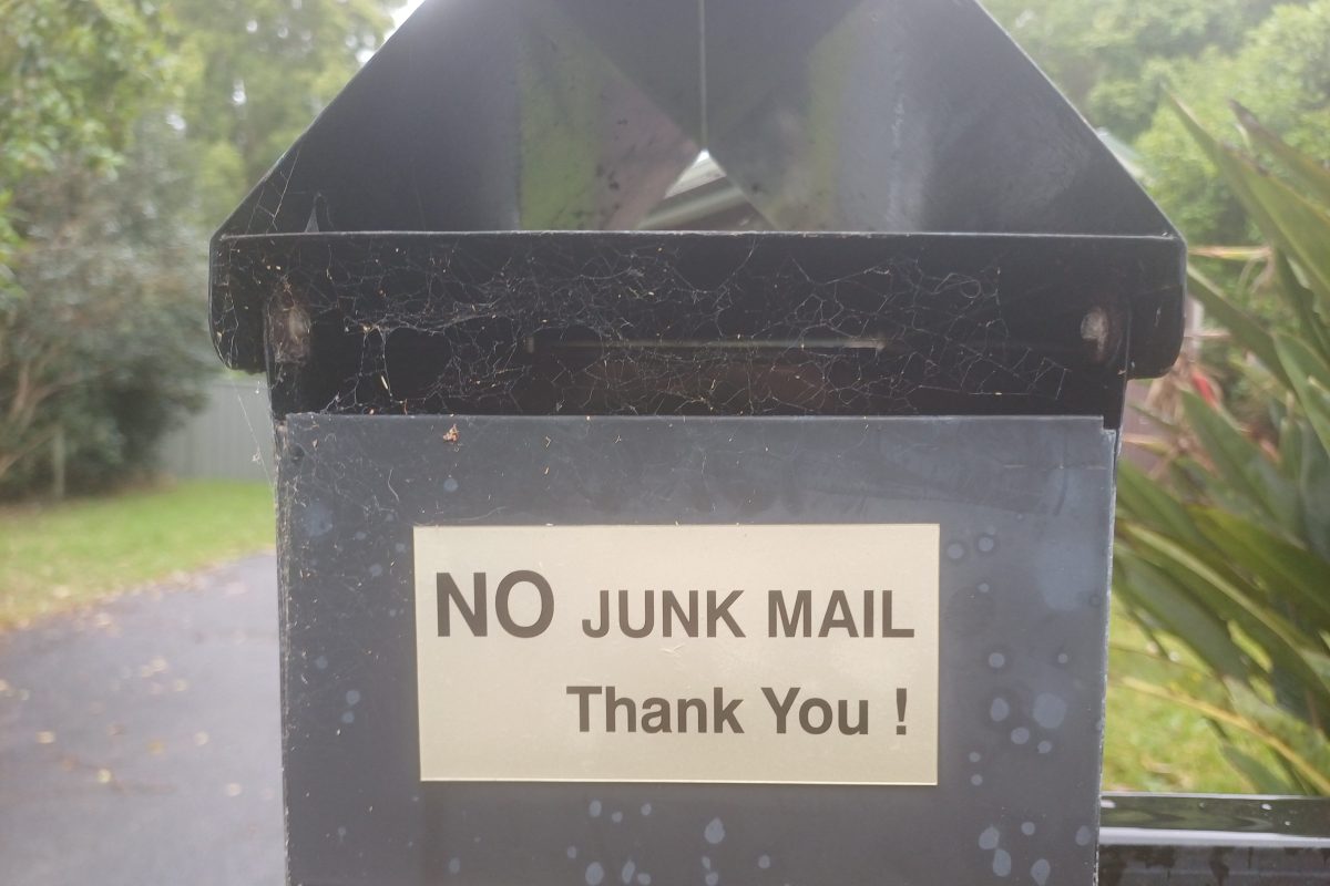 letterbox with NO JUNK MAIL sign and with spider webs across the opening