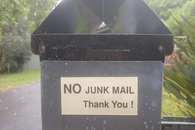 letterbox with NO JUNK MAIL sign and with spider webs across the opening